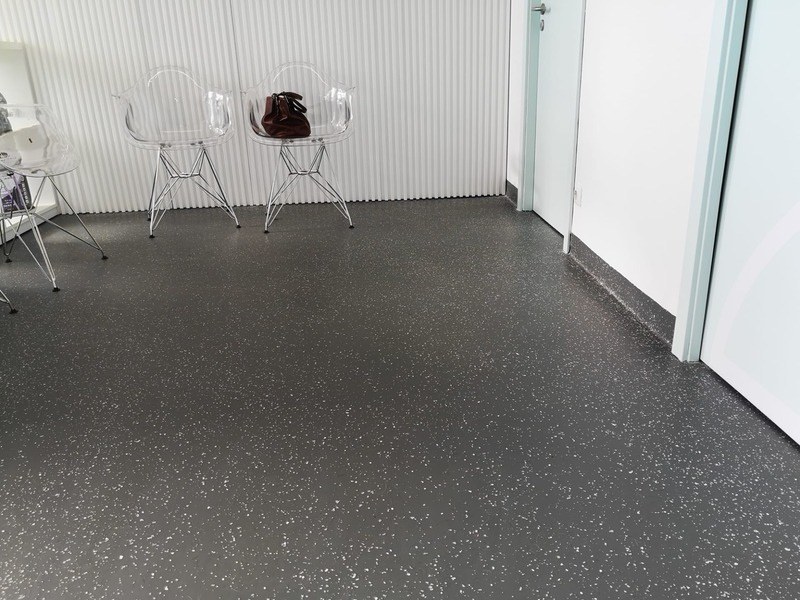 Pavimento escuro com flocos coloridos, num espaço com cadeiras